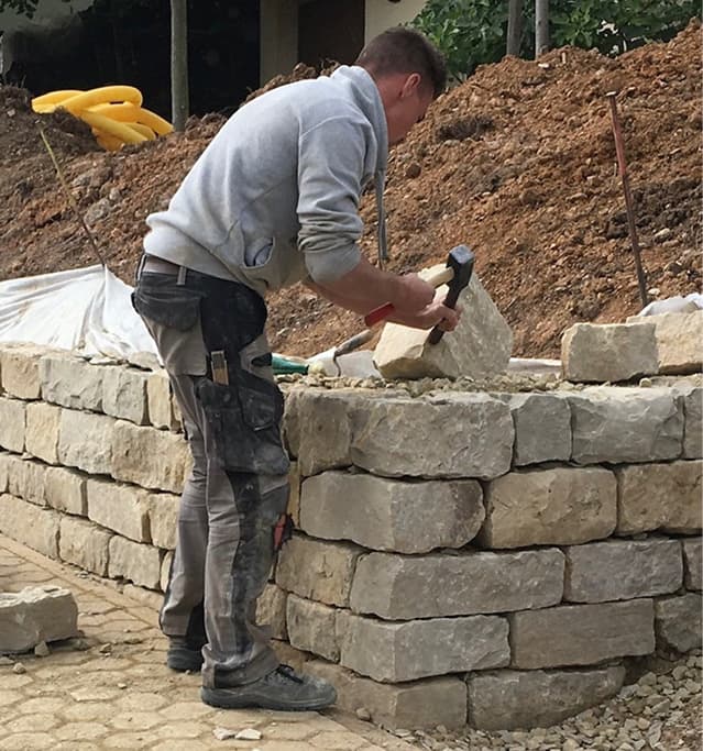 Teammitglied beim Bau einer Natursteinmauer